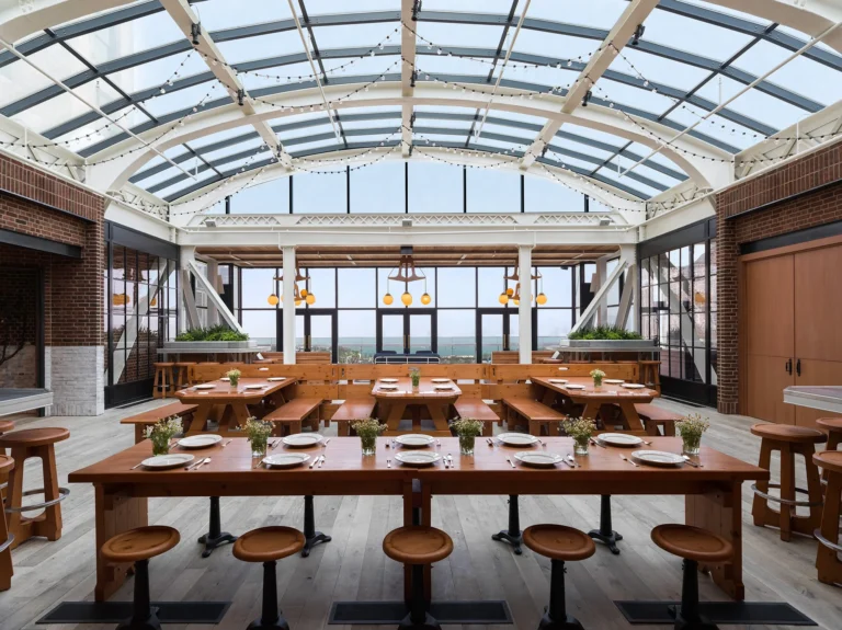 A spacious, airy dining area with a glass arched ceiling and string lights, this is one of the best event venues Chicago has to offer. Brick walls, large windows, and potted plants create a modern feel with inviting views outside.